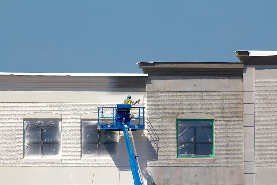 construction workers applying exterior architectural coating in urban development